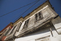 Turkey, Aydin Province, Kusadasi, Angled part view of exterior facade of Ottoman era whitewashed plaster and wooden house in the old town in late afternoon sunshine against cloudless blue sky.