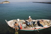 Turkey, Aydin Province, Kusadasi, Local fisherman in fishing boat with family member preparing to dive for mussels.