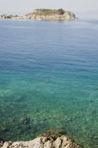 Turkey, Aydin Province, Kusadasi, View towards Guvercin Ada or Pigeon Island across clear, turquoise water.