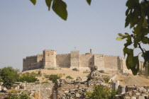Turkey, Izmir Province, Selcuk, The grand fortress of Selcuk on Ayasoluk Hill with crenellated walls and towers.  Ancient ruins in foreground.