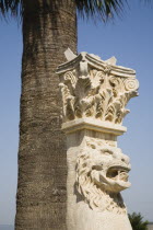 Turkey, Izmir Province, Selcuk, Corinthian column with protective lion mask beneath palm tree at ancient site of the Temple of Artemis.