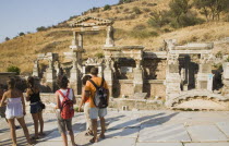 Turkey, Izmir Province, Selcuk, Ephesus, Tourists stopped to look at ruined stonework in ancient city of Ephesus on the Aegean sea coast. 