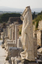 Turkey, Izmir Province, Selcuk, Ephesus, Headless statue on plinth in line of ruined pillars and empty pedestals in antique city of Ephesus on the Aegean sea coast.