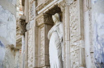 Turkey, Izmir Province, Selcuk, Ephesus, Damaged statue of female figure set in alcove of wall decorated with carvings in the antique city of Ephesus on the Aegean sea coast.