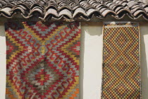 Turkey, Izmir Province, Selcuk, Kilims hanging up to dry in sunshine on walls of village house.