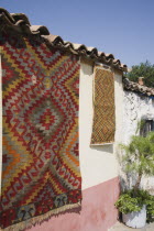 Turkey, Izmir Province, Selcuk, Kilim hanging up to dry in sun from wall of village house.