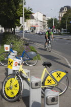 Austria, Vienna, Neubau District, Bicycles for use in city centre with approaching cyclist on road behind. 