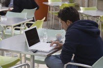 Austria, Vienna, Neubau District, Young man having coffee while surfing the net on laptop at the Museum of Modern Art, Museum Moderner Kunst Stiftung Ludwig Wien or MUMOK in the MuseumsQuartier or Mus...