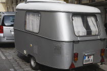 Austria, Vienna, Neubau District, Car towing vintage caravan along cobbled road.