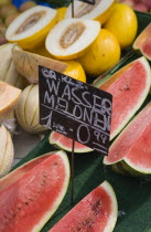 Austria, Vienna, The Naschmarkt, Display of different types of melon for sale on stall with cut slices of watermelon in foreground.