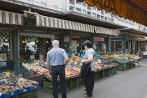 Austria, Vienna, The Naschmarkt, Customers at fresh produce stall looking at display that includes peaches, plums, pears and oranges.