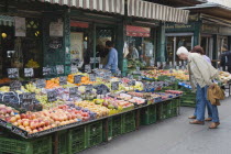 Austria, Vienna, The Naschmarkt, Customers at fresh produce stall looking at display that includes peaches, nectarines, plums and grapes.