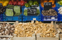 Austria, Vienna, Market stall with display including mushrooms, peppers, mange-tout and aubergines.