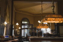 Austria, Vienna, Mariahilf District, Cafe Sperl, the preferred cafe of Adolf Hitler. Interior with customers in blur of movement at entrance and young woman using laptop in window alcove, billiard tab...