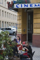 Austria, Vienna, People seated at Cafe tables on pavement outside cinema.  