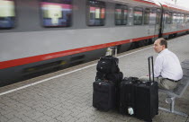 Austria, Vienna, Wien Westbahnhof, Passenger with luggage sitting on Vienna West Station with passing train. Also known as Vienna Western Station, this is a major Austrian  station and the starting po...