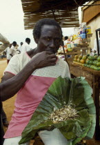 Uganda, Jinja, Man eating live white flying ants, a common snack.