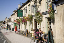 England, Gloucestershire, Burford, Tourists sat outside the Golden Pheasant Hotel in thel Cotswolds.