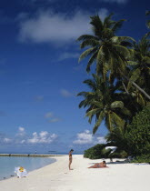 Maldives, Beach with tourists sunbathing next to the Indian Ocean.