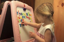 Children, Education, Young girl , Sarah, Bleau using magnetic letters on dry erase board, Keene, New Hampshire, USA.