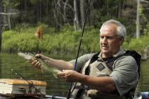 USA, New Hampshire, Sullivan, Jeff Russell holding a Pickerel fish caught by fishing from kayak on Bolster Pond.