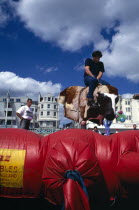 England, East Sussex, Brighton, Tourist on Seafront Bucking Bronco Ride