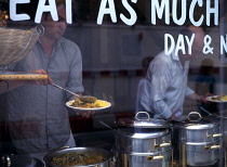 England, East Sussex, Brighton, People serving themselves vegetarian curry in the Bombay Alloo Eat as Much as you Like Indian restaurant in Ship Street.