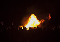 Festivals, Guy Fawkes, Bonfire, People silhouetted by flames from fire on the beach.