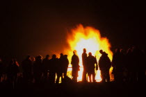 Festivals, Guy Fawkes, Bonfire, People silhouetted by flames from fire on the beach.