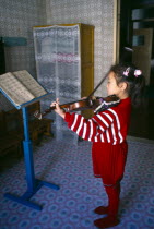 North Korea, Hwanghae Province, Sariwon, Young girl standing in front of music stand playing the violin.