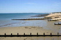 England, West Sussex, Bognor Regis, Wooden groynes at low tide used as sea defences against erosion of the shingle pebble beach.