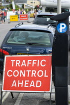 England, West Sussex, Bognor Regis, Solar panel powered Pay & Display parking meter on the sidewalk pavement for on street parking beside red Traffic Control Ahead sign with parked cars and a Road Clo...