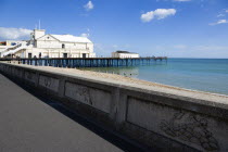 England, West Sussex, Bognor Regis, The Pier with people fishing off the end and the shingle pebble beach and the promenade with sea defence wall.