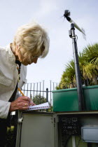 Climate, Weather, Measurements, Weather observer taking readings from the  wind speed direction monitor at Bognor Regis weather station.