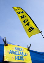 England, West Sussex, Bognor Regis, Yellow flag and sign on a tent that read Sweets and Rock Available Here under a blue sky on the Esplanade beside the beach.