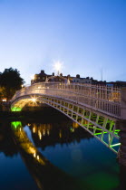 Ireland, County Dublin, Dublin City, The 1816 cast iron Ha Penny or Half Penny Bridge across the River Liffey illuminated at sunset.