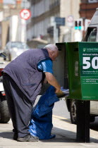 Ireland, County Dublin, Dublin City, An Post Irish postal worker emptying mail from a green modern letterbox into a sack on a pavement sidewalk.
