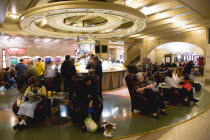 USA, New York, Manhattan, Passengers sitting in armchairs or buying food and drinks from one of the central counters in the dining concourse on the lower level.