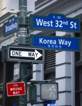 USA, New York, Manhattan, Street signs for West 32nd Street also known as Korea Way in Little Korea in Midtown with pedestrian crossing light and cycle lane wrong way sign in red and One Way sign.