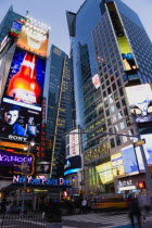 USA, New York, Manhattan, People walking at night in Times Square at the junction of 7th Avenue and Broadway by the New York Police Department station below buildings with advertising on large video s...