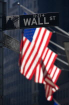 USA, New York, Manhattan, Road signs for Wall Street and Broad Street with American Stars and Stripes flags flying from the Stock Exchange building.