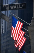 USA, New York, Manhattan, Road signs for Wall Street and Broad Street with American Stars and Stripes flags flying from the Stock Exchange building.