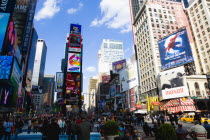 USA, New York, Manhattan, People walking in Times Square at the junction of 7th Avenue and Broadway below buildings with advertising on large video screens with yellow taxi cabs driving down 7th Avenu...