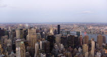 USA, New York, Manhattan, View from Empire State building over midtown skyscrapers and East River towards Queens and Long Island with Art Deco Chrysler Building illuminated at dusk.