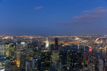 USA, New York, Manhattan, View from Empire State building over midtown skyscrapers and East River towards Queens and Long Island with Art Deco Chrysler Building illuminated at sunset.