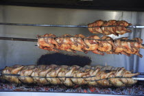Albania, Tirane, Tirana, Spit-roasted chicken cooking over hot embers in the Avni Rustemi Market.