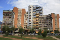 Albania, Tirane, Tirana, Apartment blocks with shops below, overlooking road and area of grass and trees.
