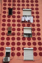 Albania, Tirane, Tirana, Part view of apartment block painted pink with pattern of red circles. Windows with pot plants on ledges and washing hanging up to dry.
