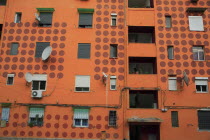 Albania, Tirane, Tirana, Part view of exterior facade of apartment block painted orange with pattern of red painted circles. Multiple windows, satelite dishes, balconies.