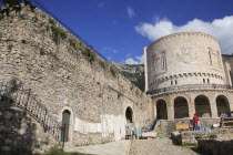 Albania, Kruja, Exterior walls of Kruja Castle and Skanderbeg Museum with craft and souvenir stalls in foreground and single person.